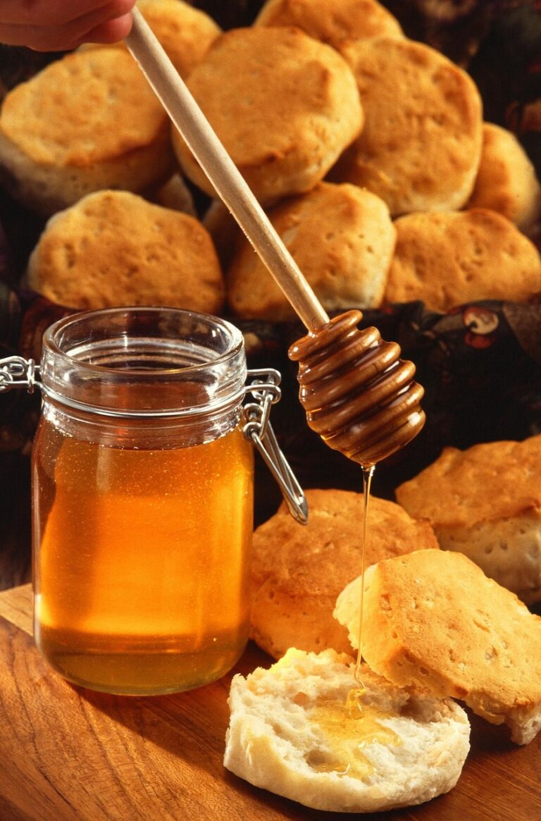 Un pot de miel, dont une partie est versée sur des scones